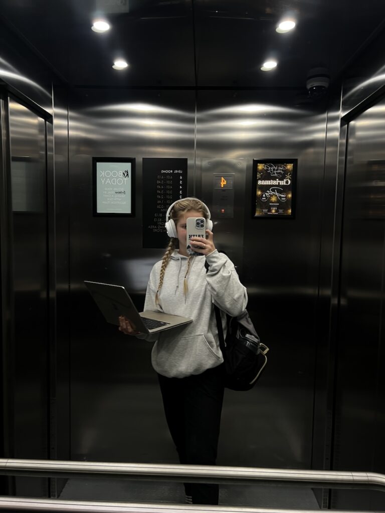 girl standing in elevator with laptop in hand