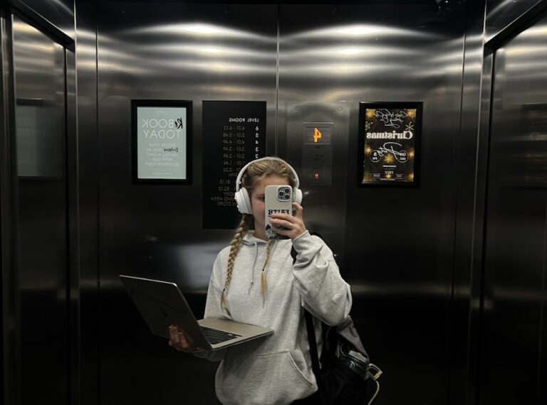 girl standing in elevator with laptop in hand